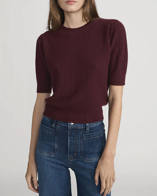 Front view of a short-sleeve textured knit top in deep burgundy with a ribbed hem and crew neckline, paired with high-waisted blue jeans.