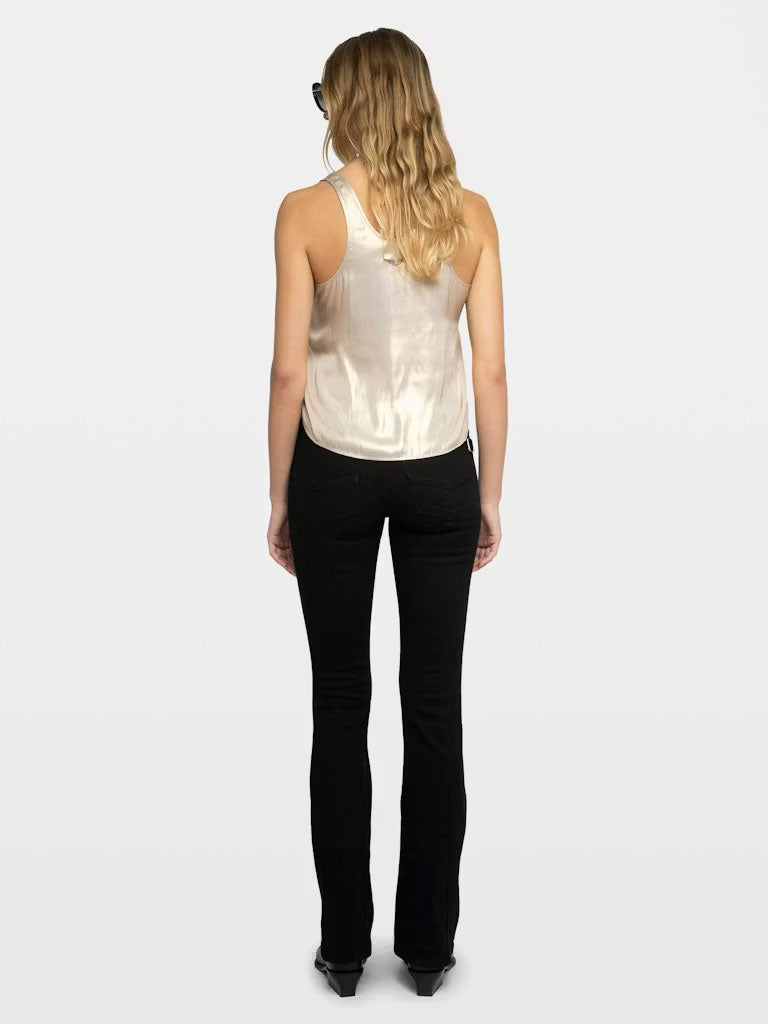 A back view of a person wearing a cream-colored satin tank top paired with fitted black pants and black pointed-toe shoes. The top has a soft sheen and a relaxed, slightly draped fit.