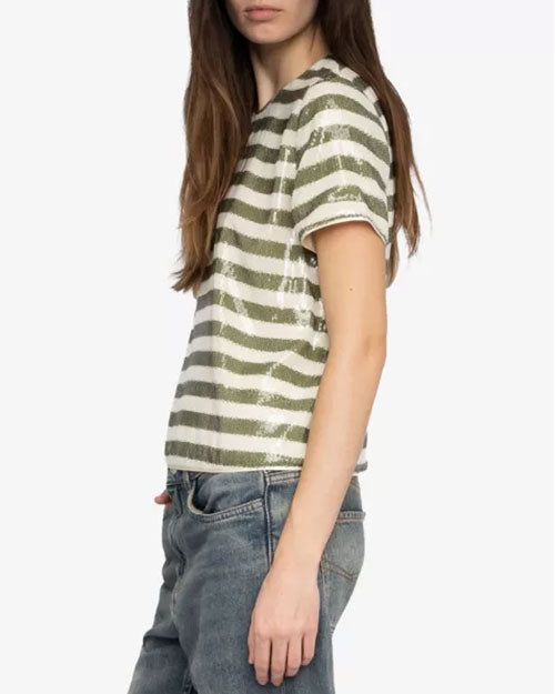 A person is shown from the side wearing a short-sleeve T-shirt with horizontal olive green and white stripes. The shirt has a relaxed fit and a round neckline. The outfit includes high-waisted, faded blue jeans with a straight-leg cut. The person’s left arm is resting naturally by the side.
