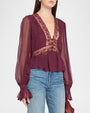 Plum chiffon blouse with sheer long sleeves, a deep V-neckline, lace panel detailing, a gathered peplum hem, and ruffled cuffs, styled with light-wash jeans.