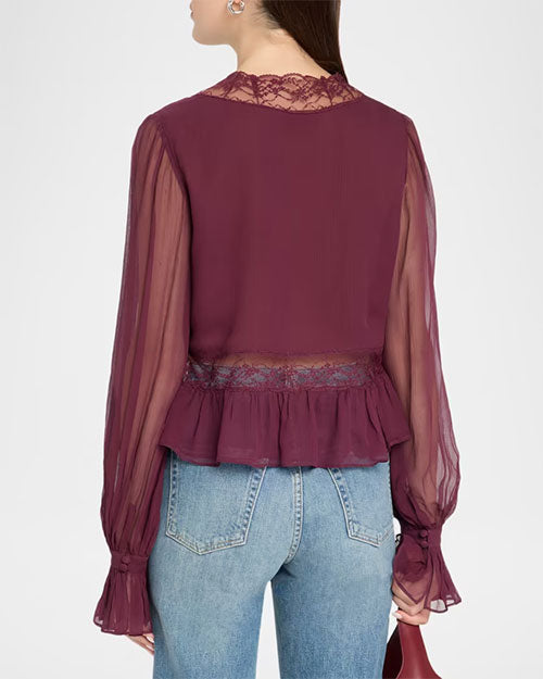 Back view of a plum chiffon peplum blouse with sheer long sleeves, lace trim at the neckline and waist, and ruffled cuffs, styled with light-wash jeans.