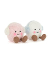 Two round plush toys with smiling faces and earmuffs—one pink with white earmuffs, the other white with light blue earmuffs—both featuring black eyes, rosy cheeks, and brown feet.