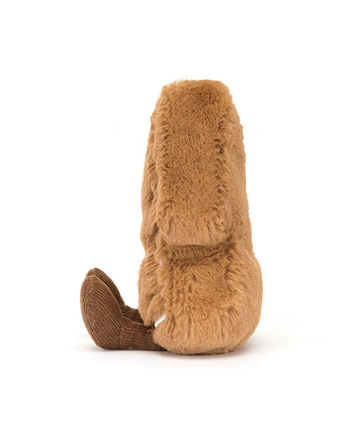 Side view of a plush Christmas tree shaped toy with light brown fluffy fur and brown corduroy feet, sitting upright.