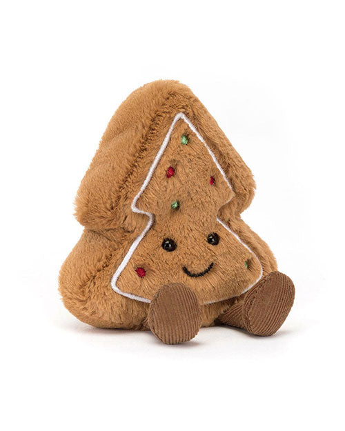 Plush toy shaped like a gingerbread Christmas tree with a soft brown fuzzy texture, white icing-like outlines, colorful sprinkle-like decorations, black eyes, a smiling mouth, and small corduroy feet.