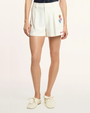 Person wearing cream shorts with floral embroidery on a white background