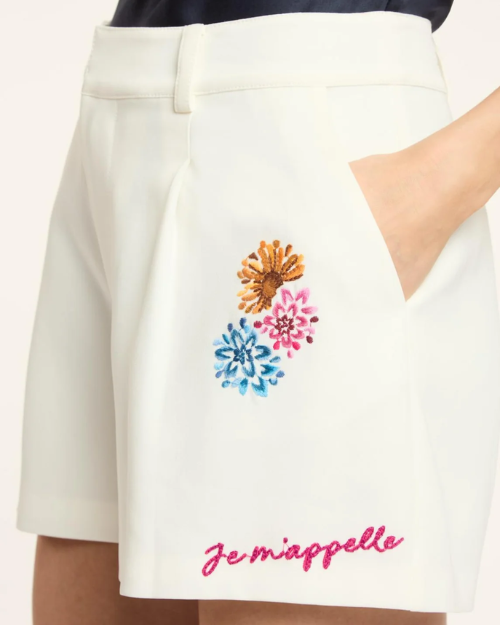 White skirt with colorful floral embroidery and 'Je m'appelle' text on a white background