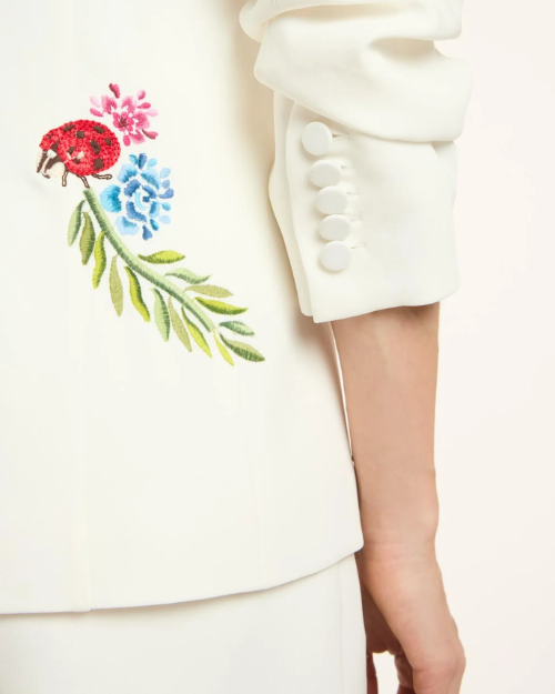White blazer with floral embroidery on a plain background