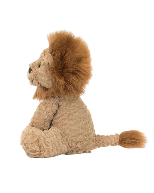Side profile of a plush toy lion with a light brown textured body, darker brown mane and tail tip, and stitched facial features including eyes, nose, and mouth.
