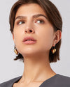 A woman adorned with shiny gold hoop heart earrings, highlighting her fashionable and chic appearance.