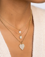 Close-up of a person wearing gold necklaces with heart pendants.