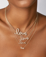 Person wearing multiple layered gold necklaces, each featuring a script-style “love” pendant with small sparkling stones against a white background.