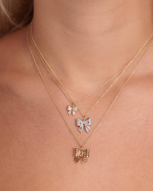 Gold bow necklaces on a person's neck