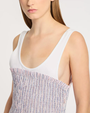 Woman wearing a white tank top with a pink striped dress on a plain background