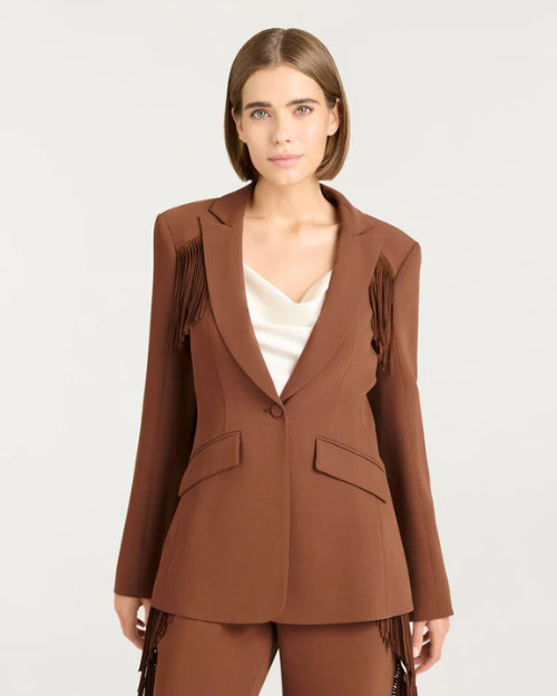 Woman wearing a brown suit with fringe details on a white background