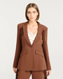 Woman wearing a brown suit with fringe details on a white background