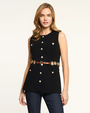 Woman wearing a black sleeveless top with buttons and jeans on a white background