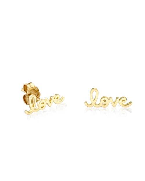 Gold 'love' stud earrings on a white background