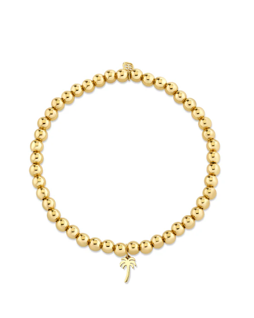 Gold beaded bracelet with a small gold palm tree charm on a white background