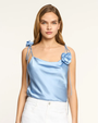 Woman wearing a light blue satin top with floral details on a white background