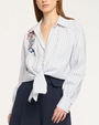 Woman wearing a white and blue striped shirt with a floral blouse underneath on a white background