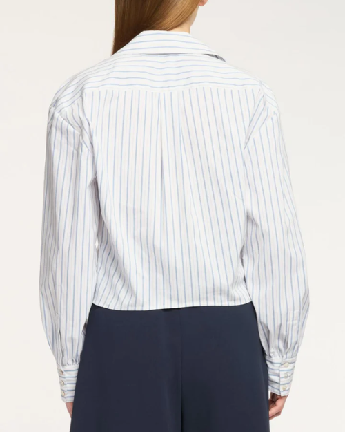 Person wearing a white shirt with blue vertical stripes and navy pants on a white background