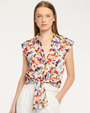 Woman wearing a colorful floral sleeveless blouse against a white background
