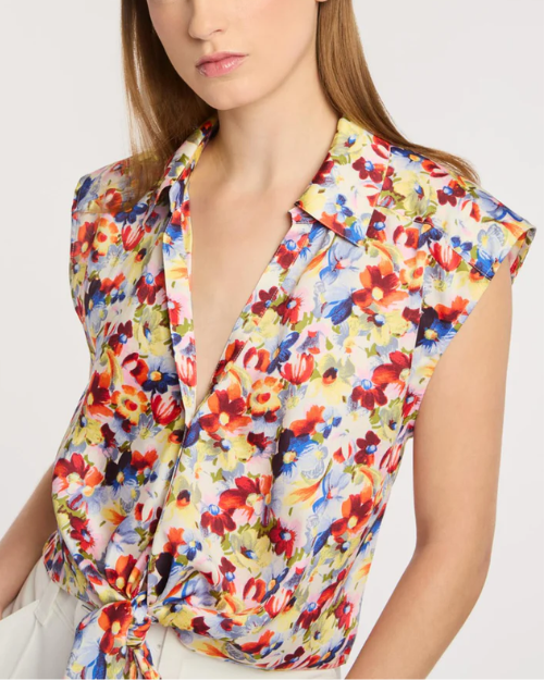Woman wearing a colorful floral sleeveless top against a plain background