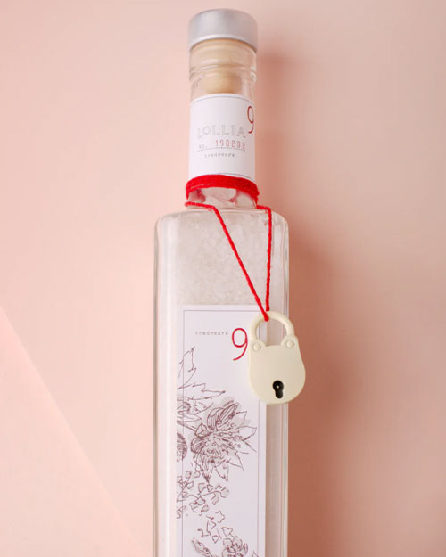 A bottle of sea salt tied with a red ribbon, showcasing a decorative touch for bathroom use.