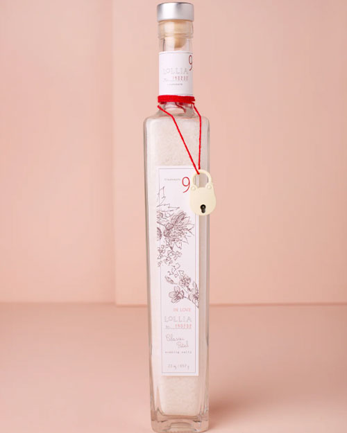 A clear bottle filled with sea salt, elegantly adorned with a red ribbon for a charming presentation.