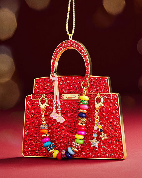 A red Christmas ornament shaped like a purse, adorned with colorful beads hanging from it.