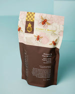 A bag of salt soak with a vibrant flower design, showcasing bees around it.