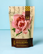 A bag of bath salts, featuring delicate pink petals and a soothing, aromatic blend for a relaxing bath experience.