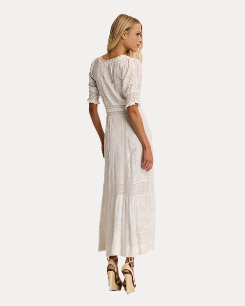 Back view of a woman wearing a white lace dress against a plain background