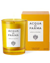Acqua Parma orange candle displayed in a glass holder, emitting a warm glow against a neutral background.