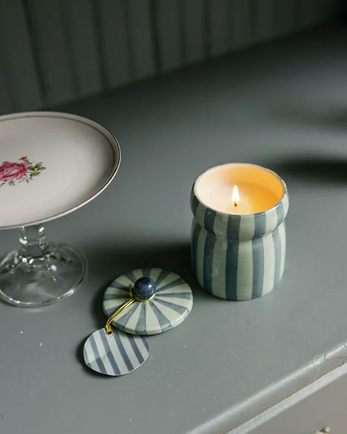 A lit candle next to a plate holding a cup and another plate, enhancing the table's ambiance.
