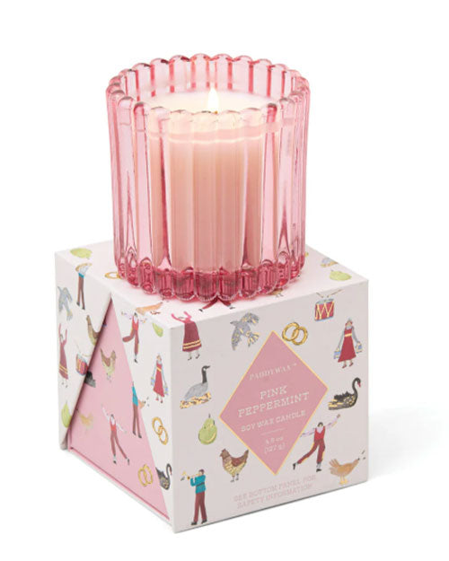 A pink candle atop a Christmas decorated box, showcasing a cohesive and stylish arrangement.