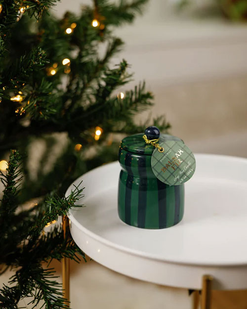 A green and blue candle placed on a white table, showcasing its vibrant colors against the neutral background.