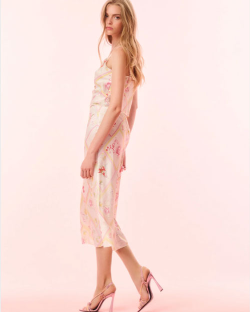 A model showcases a pink floral top and skirt featuring a high neckline, highlighting a vibrant and elegant design.