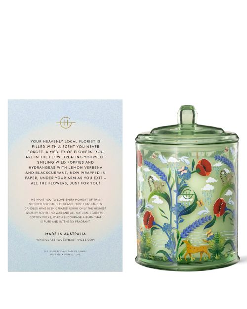 Indulge in the soothing atmosphere created by the Glasshouse "Flower of the Forest" candle, featuring a vibrant floral design and accompanied by an informational card detailing its contents.