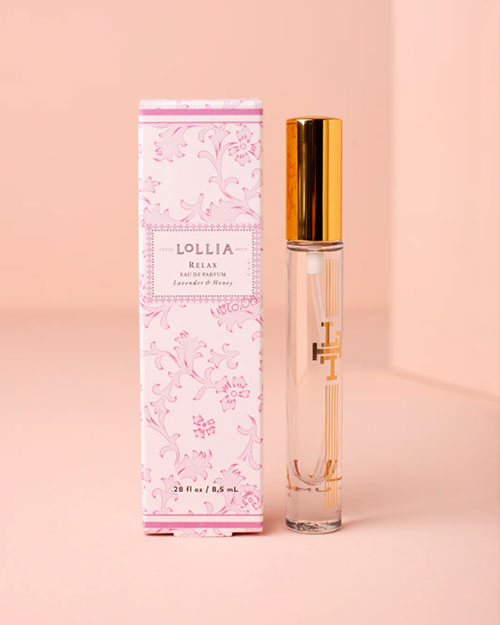 A perfume bottle adorned with elegant gold accents, standing next to a white and pink florally designed box with the label "LOLLIA" in the center, placed in front of a pink background.