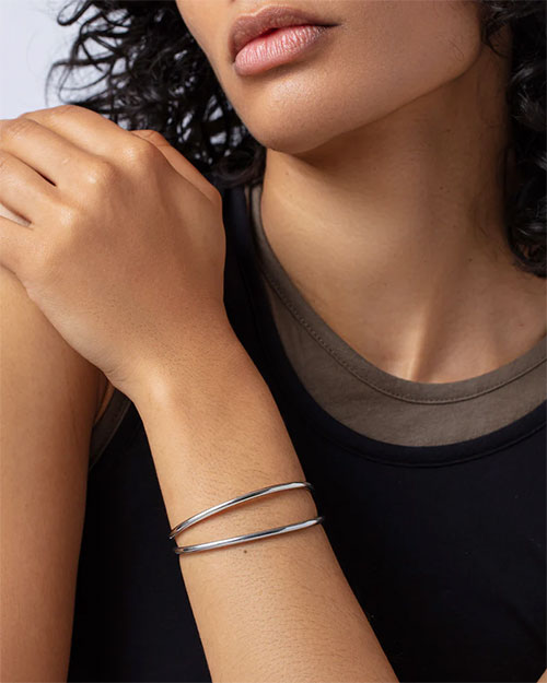 A woman dressed in a black top, adorned with a silver bracelet, highlighting her elegant fashion choice.
