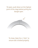 A bracelet displaying instructions to push down on the highest point of the clasp to open it.