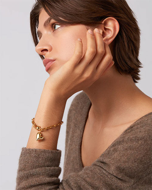 A woman showcases a gold bracelet and a gold chain, highlighting her elegant jewelry choices.