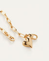 A gold heart charm attached to a delicate chain bracelet, showcasing a simple yet elegant design.