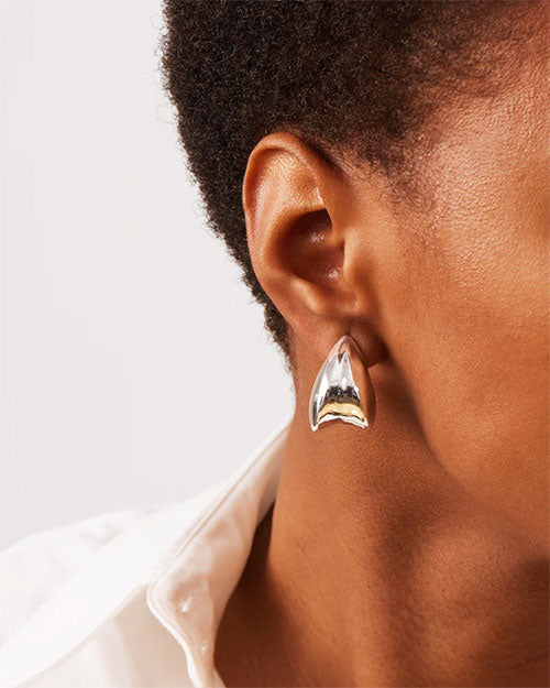 A woman is wearing a silver earring featuring a stylish curved design.
