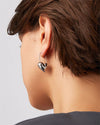 A woman wearing stylish silver hoop earrings shaped like hearts, showcasing a modern and elegant design.