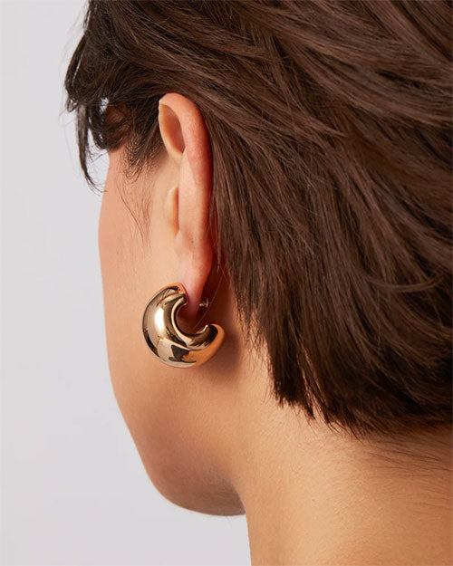 A woman’s back showcasing her short hair and stylish gold earrings.