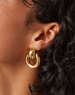 Close-up of a woman adorned with gold hoop earrings, highlighting their stylish appearance.