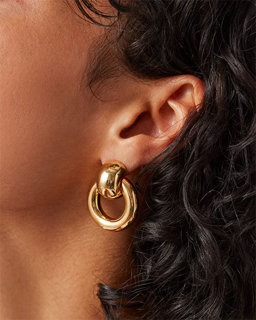Close-up of a woman adorned with gold hoop earrings, highlighting their stylish appearance.