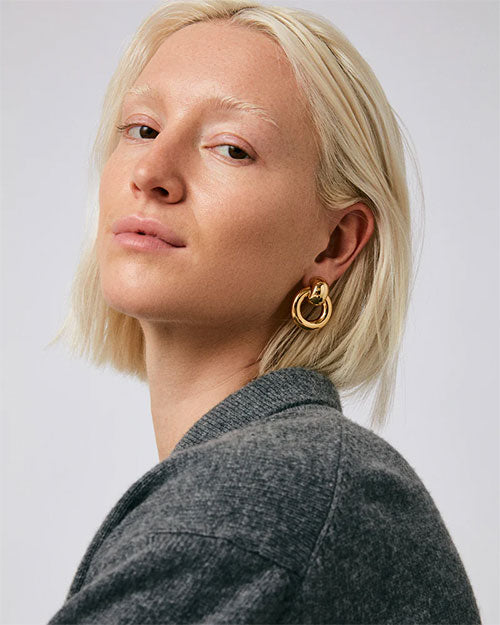 A woman wearing a gold hoop earring, emphasizing elegance and contemporary fashion in her look.